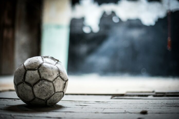 A worn football resting alone on an empty floor, symbolising the uncertainty and pressure of the academy journey.