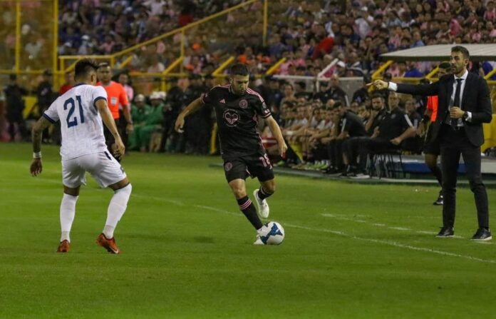 David Dóniga Lara coaching on the sidelines during El Salvador’s match against Inter Miami, with Jordi Alba controlling the ball.