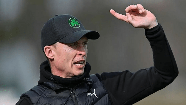 Petr Ruman wearing a black cap and Puma jacket, gesturing during a football training session.