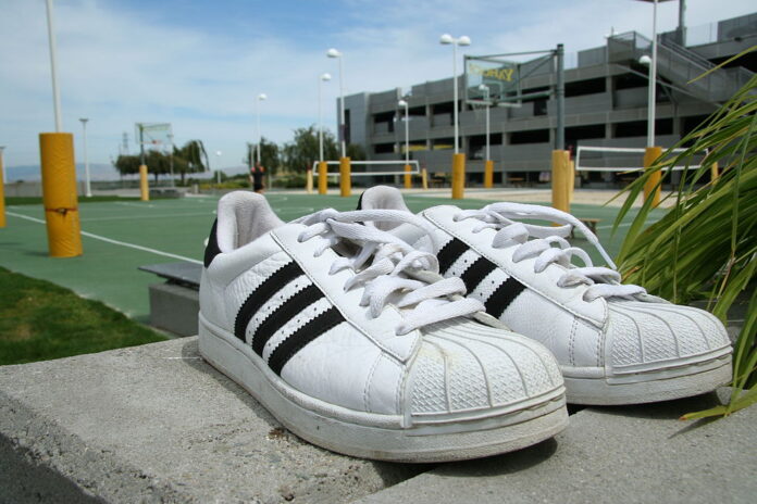 Adidas Superstar sneakers placed outdoors, symbolizing the timeless connection between sport, fashion, and culture.