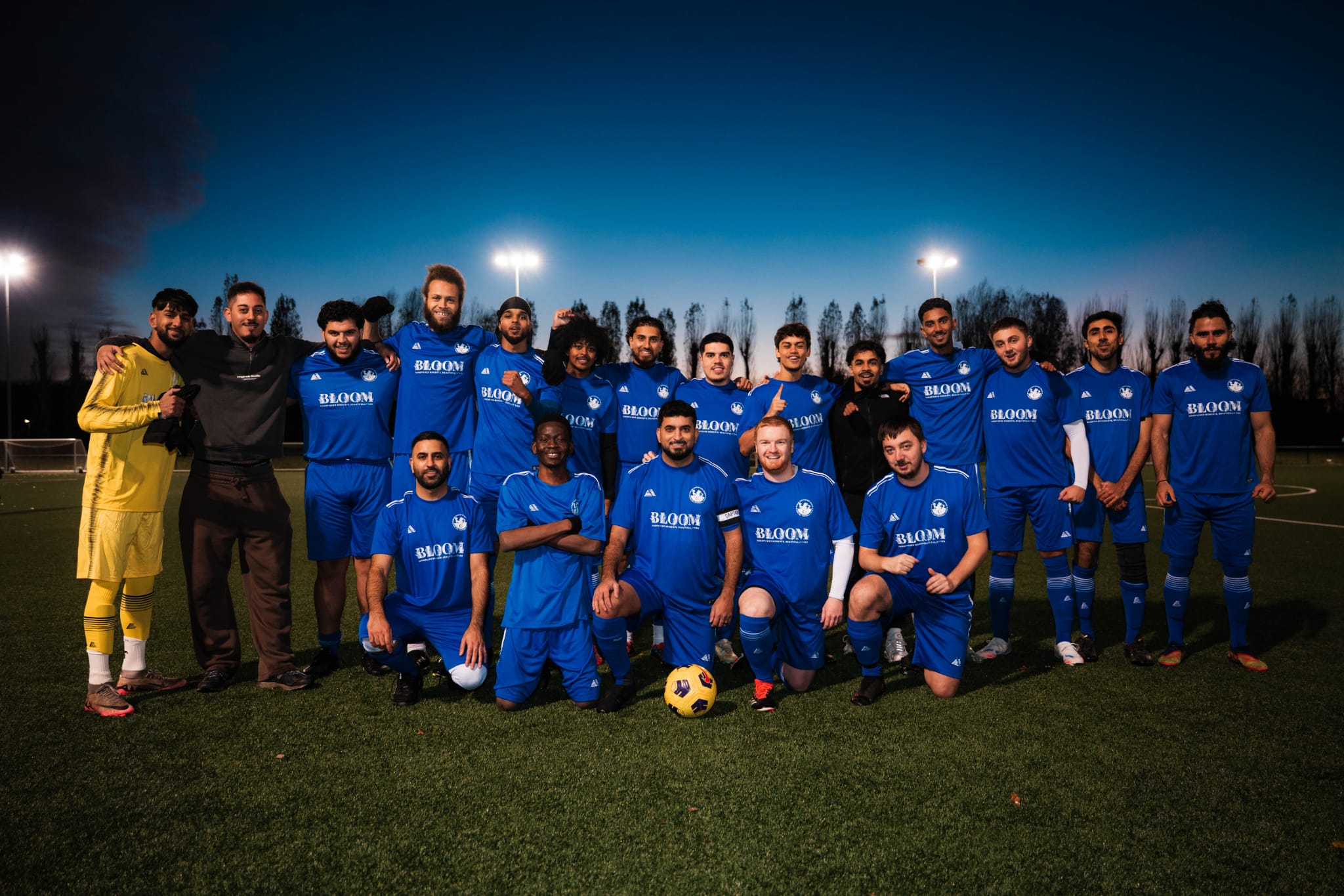Chelsea Muslim Supporters Group team in blue kits posing together under evening sky.