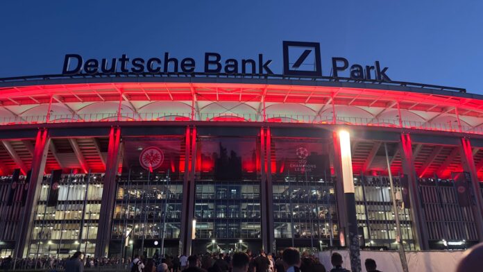 Deutsche Bank Park stadium lit in red at night showcasing prominent naming rights branding above the main entrance.