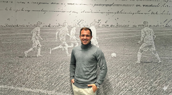 Kevin Cauet stands in front of a football mural, reflecting his global career in coaching, scouting and player development.