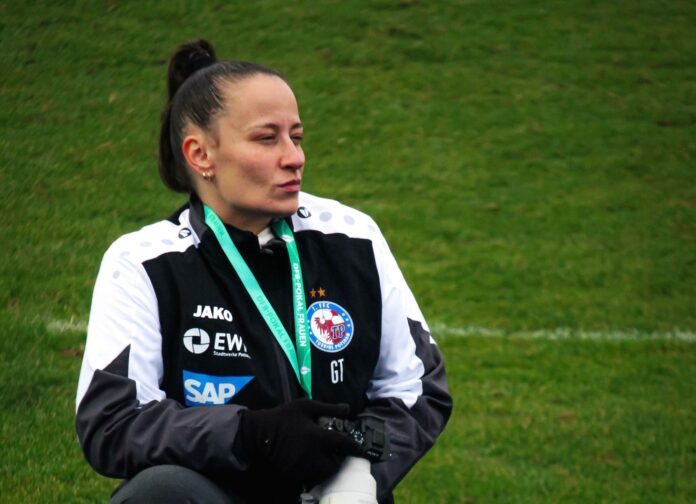Gamze Tutaker working pitchside during a women’s football match, capturing moments from the technical area.