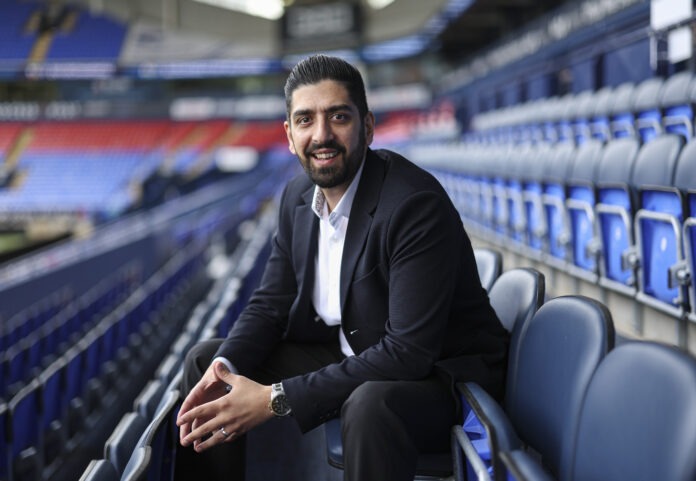 Niaz Shazad, football executive and CFO, seated in a stadium, reflecting leadership and governance in modern football.