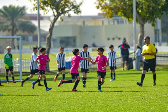 Young football players celebrating together during a grassroots match, reflecting confidence, teamwork, and emotional development on the pitch.