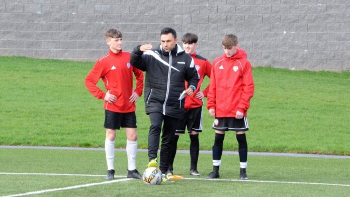 Norberto Rodrigues Da Silva gives tactical instructions to youth players during a training session on the pitch.