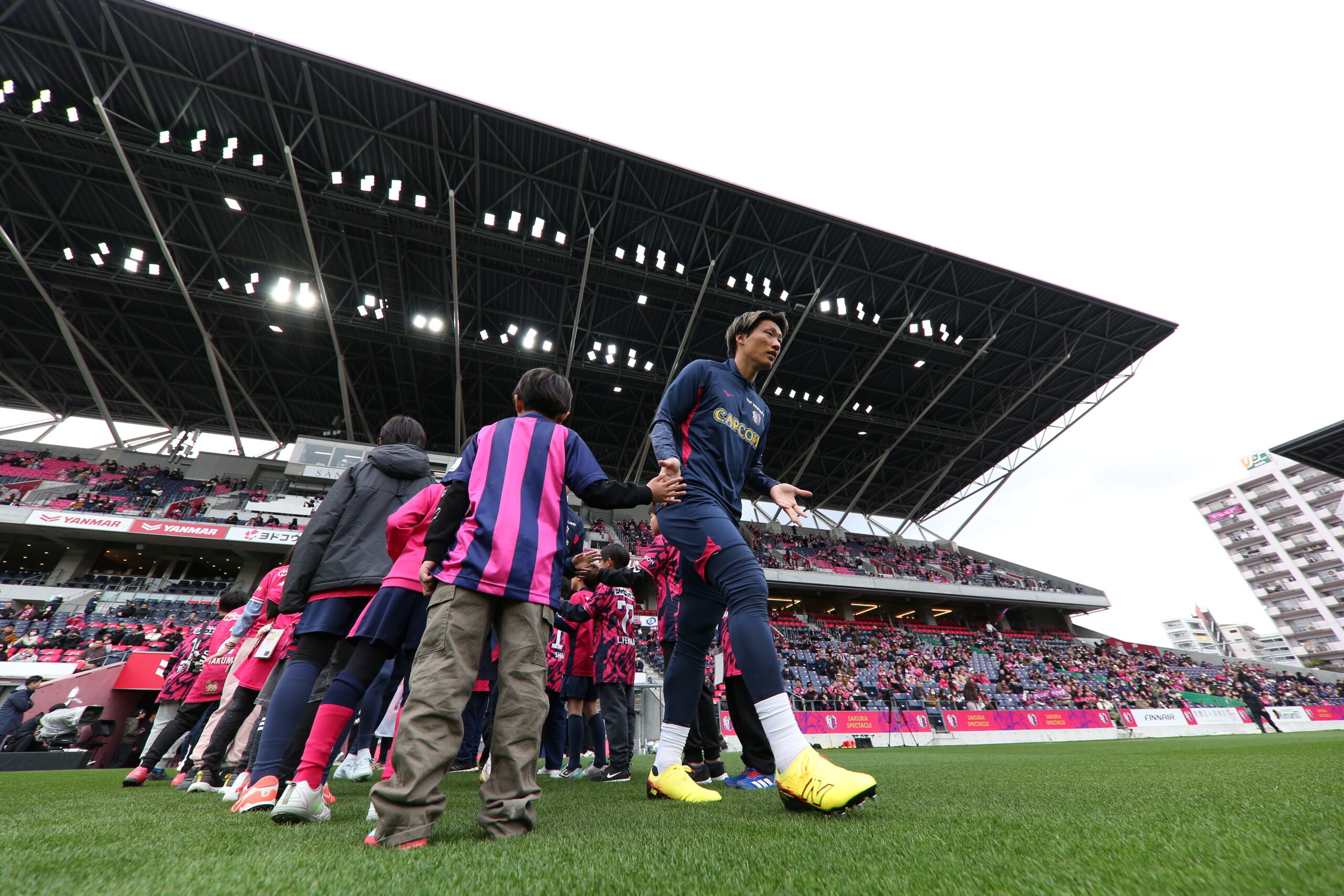 Cerezo Osaka player greets young fans on the pitch highlighting close bond between team and supporters