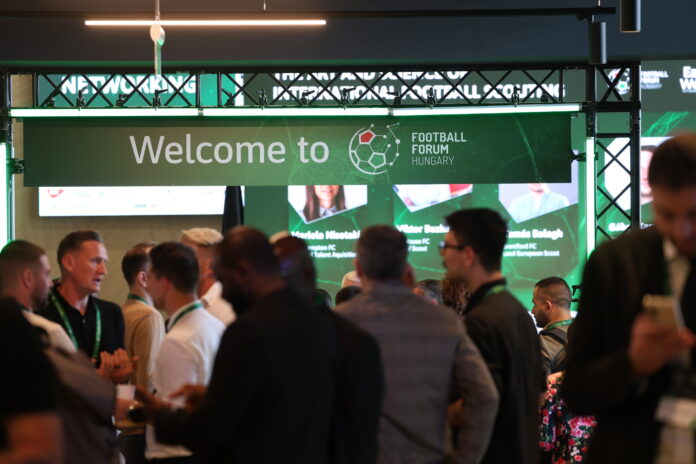 Attendees networking at Football Forum Hungary event under welcome banner at conference venue in Budapest.