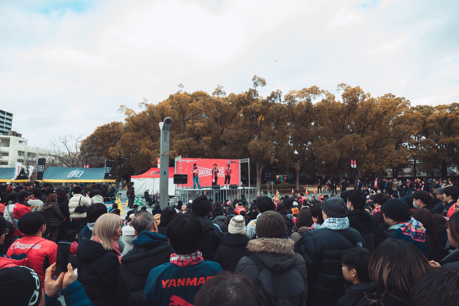 Fans gather at Cerezo Osaka WAKUWAKU Stage pre match, highlighting community engagement and fan experience