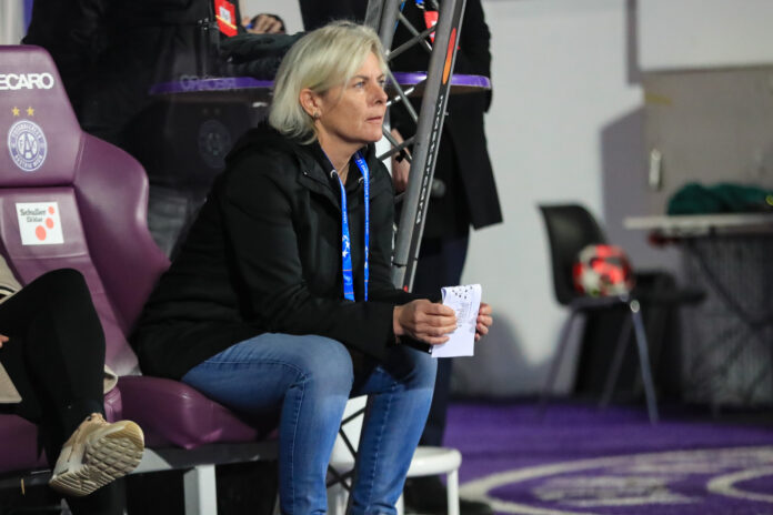 Tanja Schulte observing a match from the bench, reflecting leadership and tactical focus in women’s football