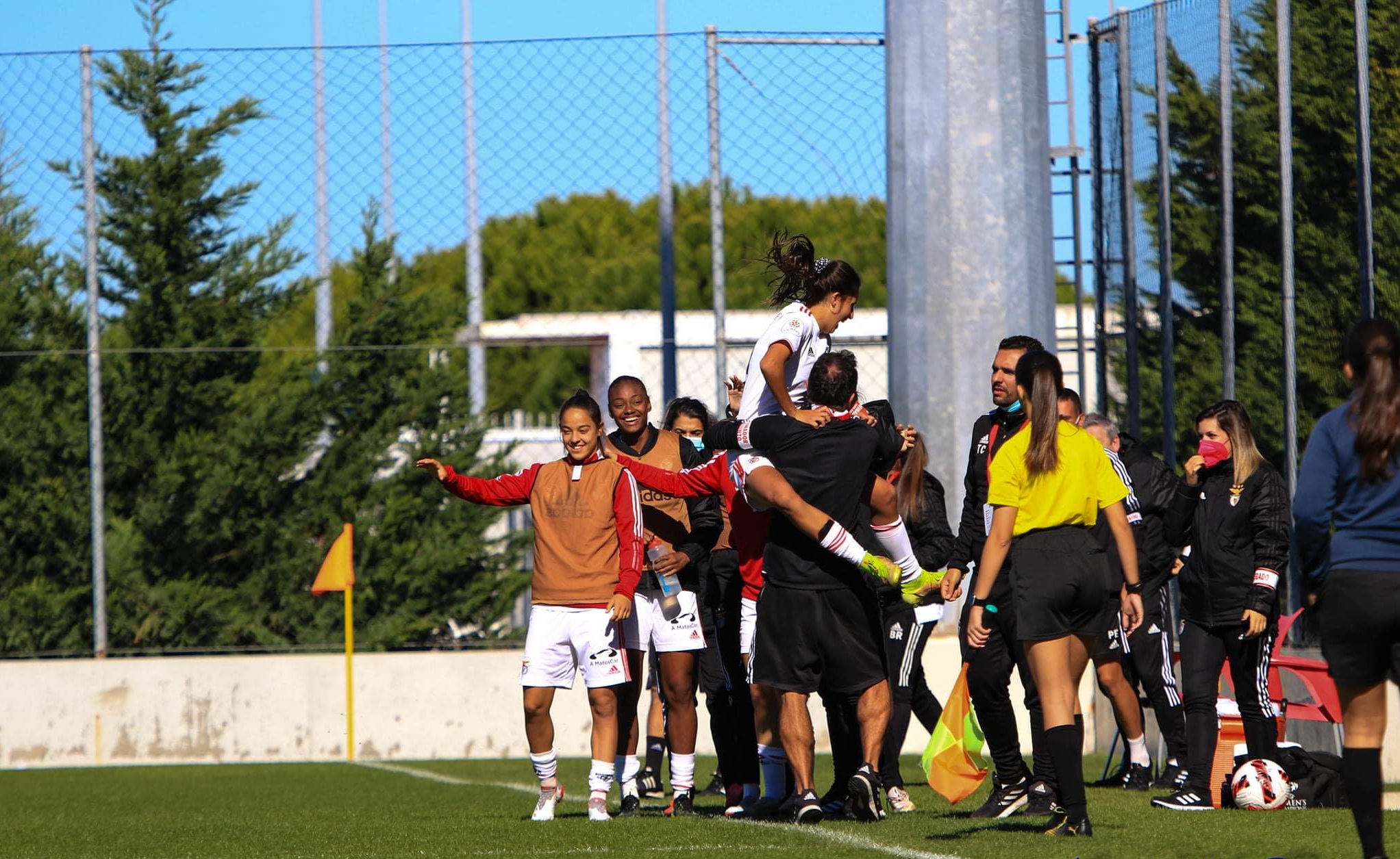 Women’s football players celebrating with coaching staff after a match.