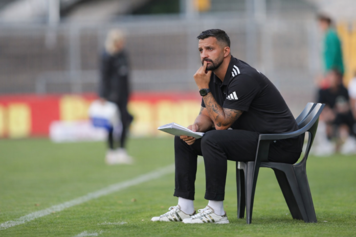 Aytaç Sulu observes a training session from the touchline during a football coaching session.
