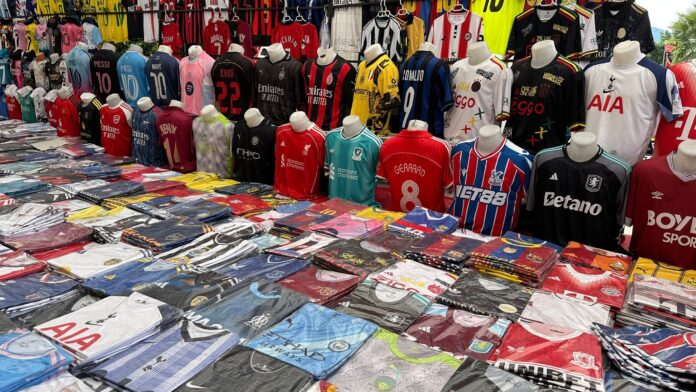 Collection of football shirts and retro kits displayed at a football merchandise market stall.