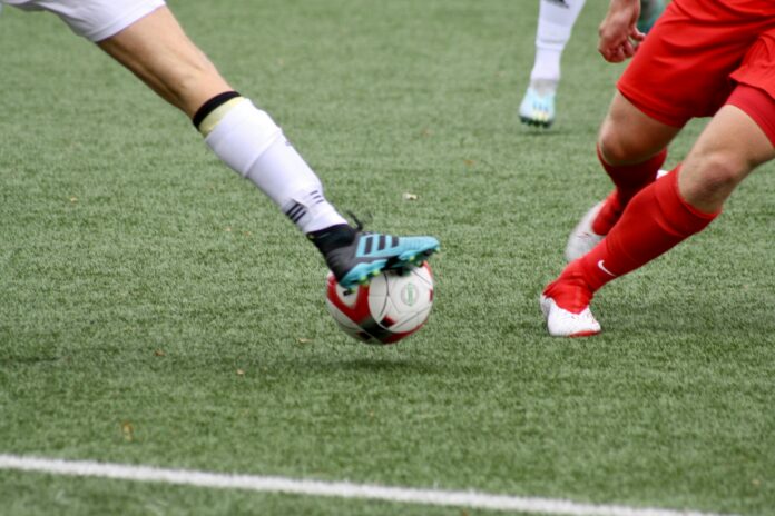 Football players challenge for possession during a match, reflecting the pressure and intensity of competitive football