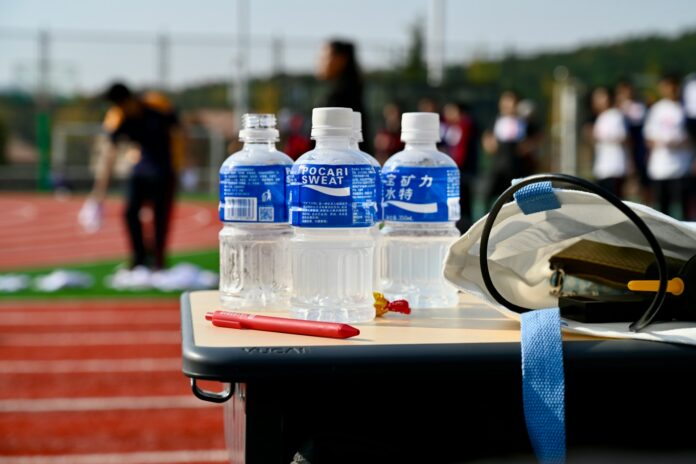 Hydration bottles beside a sports track, highlighting heat adaptation and recovery for the 2026 World Cup.