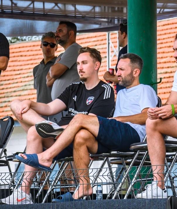 Football scout watching from the stands during live player evaluation at a match.