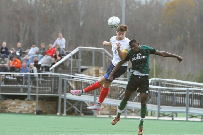 Louisburg player winning a header during an American college soccer match, reflecting U.S. player pathway development.