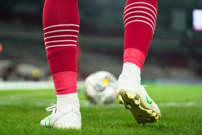Football player standing over a ball before a key moment, reflecting decision-making and career progression.