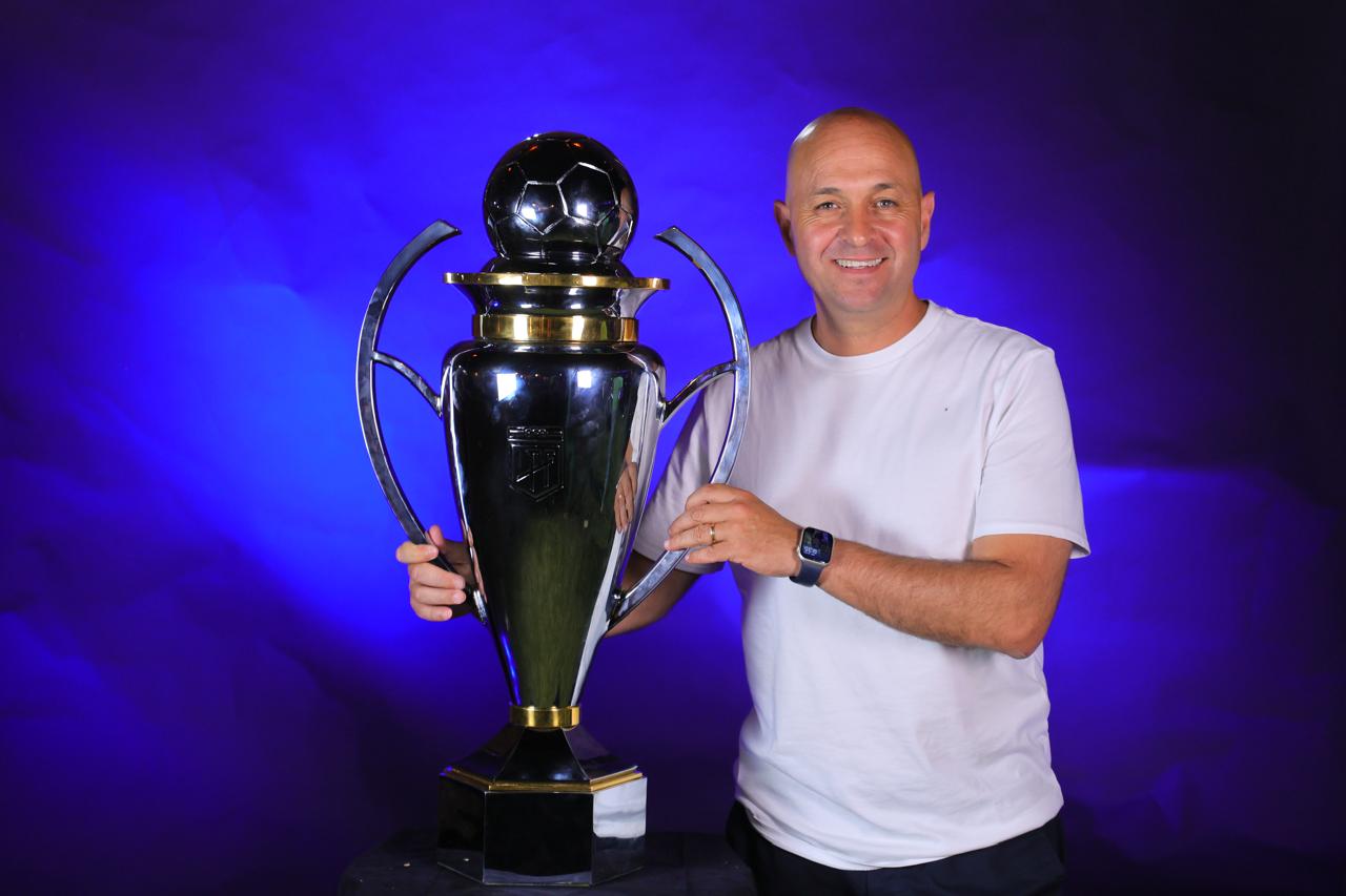 Sebastián Pait posing with a Vélez trophy, reflecting success in Argentine football development.