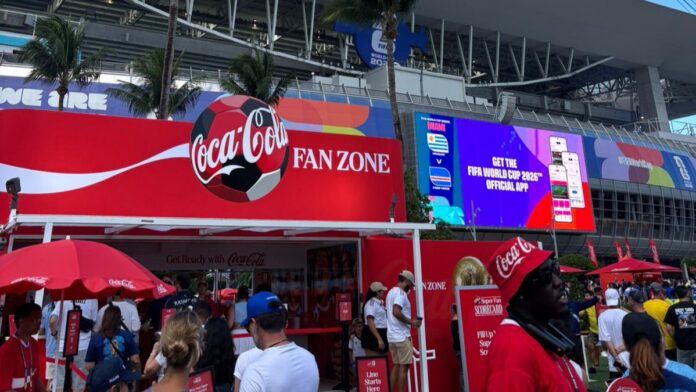 Fan Zone del Mundial con activaciones de marca y pantallas frente a un estadio de fútbol.