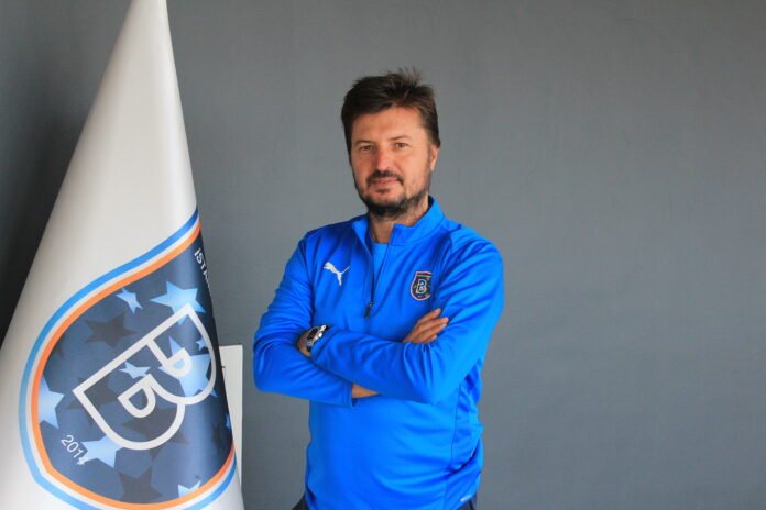 Ahmet Geçer in Başakşehir training kit beside the club flag