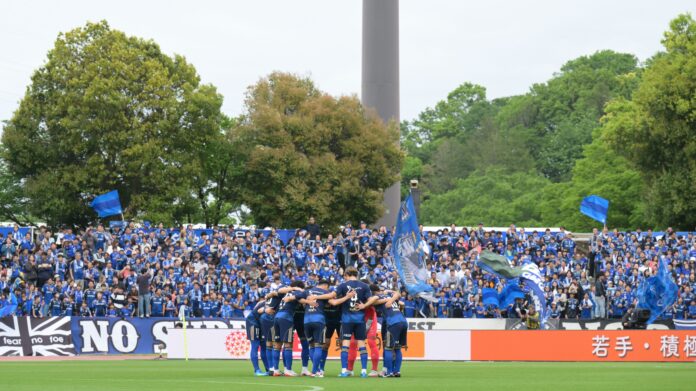 FC Machida Zelvia players huddle in front of supporters during a J.League match