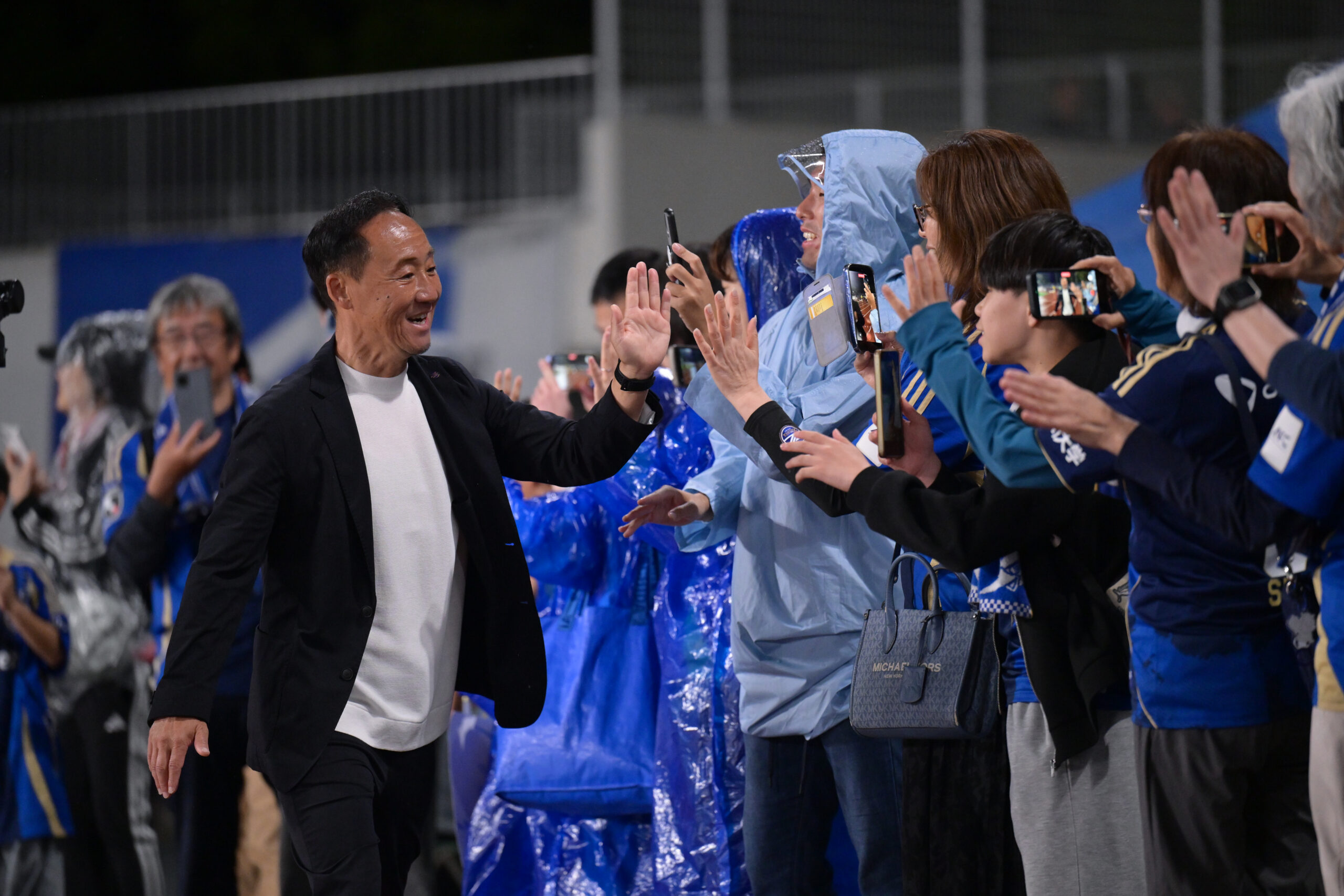 FC Machida Zelvia leadership member high-fives supporters after a match