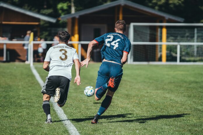 Footballers compete for the ball during a grassroots match on a local pitch