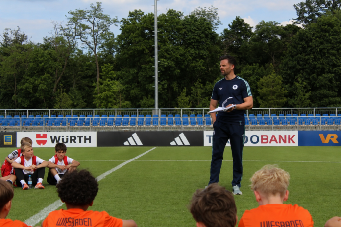 Michael Duda coaches young football players during a youth development session