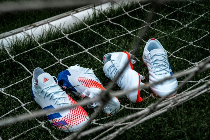 Adidas football boots in a goal net representing sponsorship, brand partnerships and commercial deals in football.