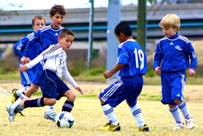 Youth footballers competing during a match, illustrating differences in physical development and biological age.