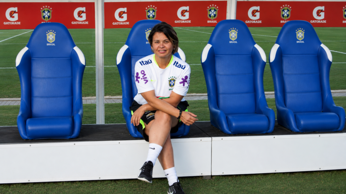 Sandra Santos seated in the Brazil national team dugout during her work in women’s football development.
