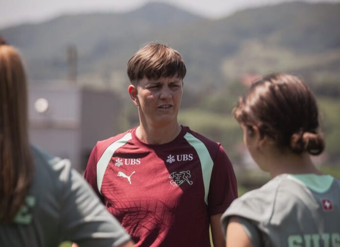 Anne Pochert speaks with Switzerland youth players during an outdoor training session.