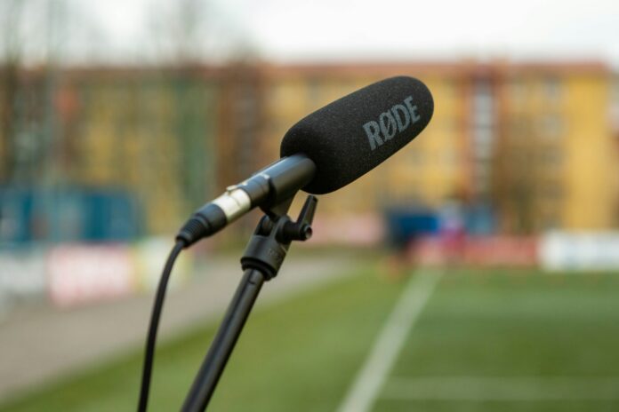 Microphone beside a football pitch representing athlete communications, public identity and digital governance.