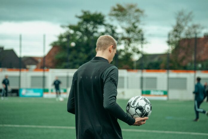 Footballer holding a ball on a training pitch during the period between transfer windows.
