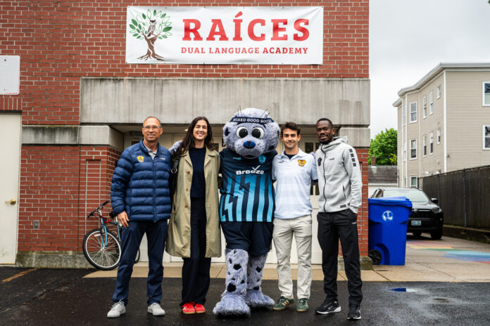 Sean Carey stands with Rhode Island FC representatives and its mascot outside Raíces Dual Language Academy.