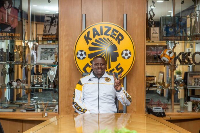Tera Maliwa sits before the Kaizer Chiefs crest at the club’s offices, surrounded by historic football memorabilia.